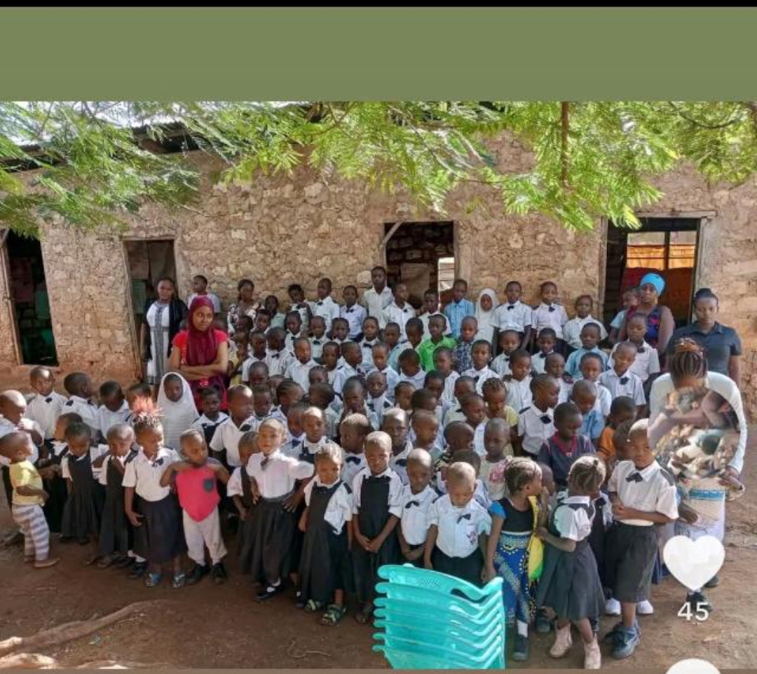 Group photo of Eagle Wings Lighthouse Academy pupils and staff outside a stone building in the early days of the school in 2021