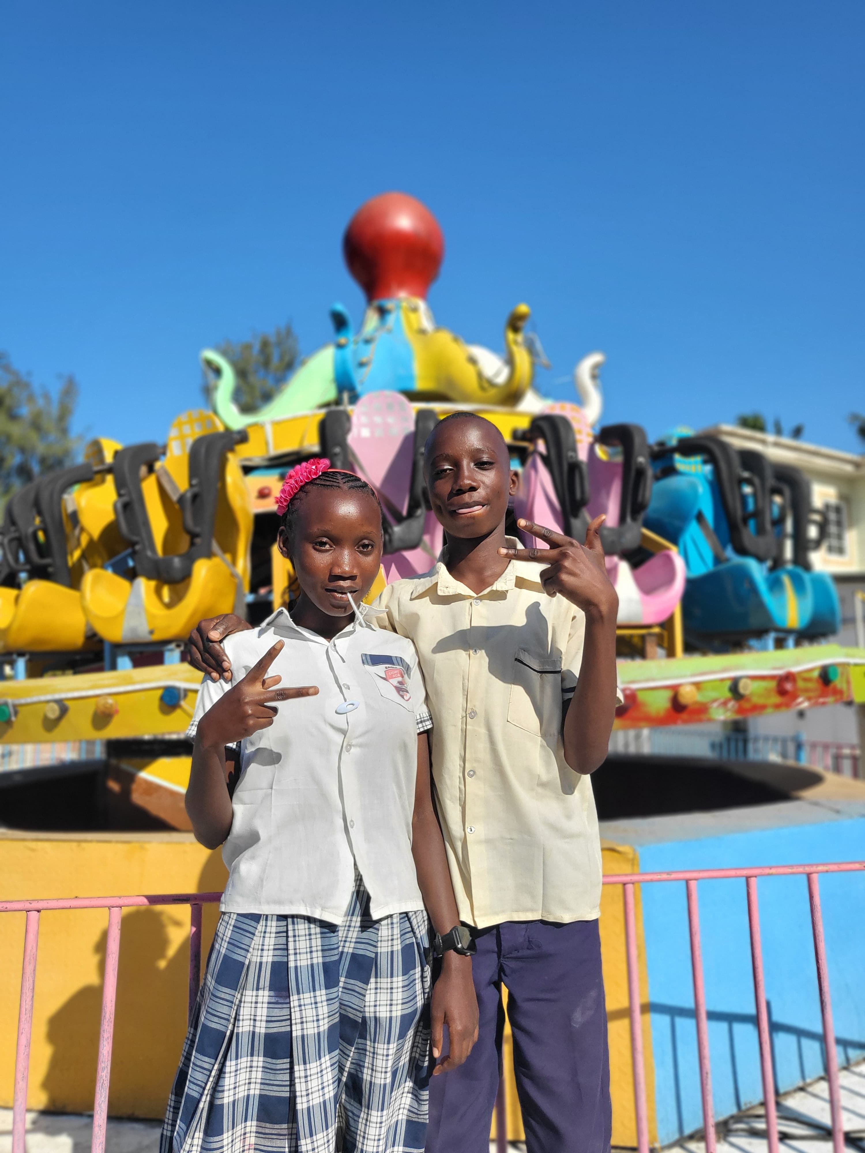 Two students posing in front of a carnival ride at an amusement park